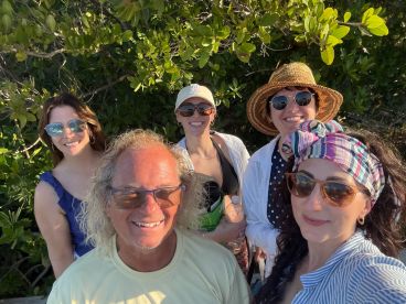 A cheerful group of friends poses for a selfie amidst lush greenery, capturing a joyful moment during their outdoor adventure.