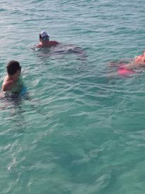 A group of friends enjoys a refreshing swim in the clear turquoise waters, capturing the essence of fun and adventure on their aquatic getaway.