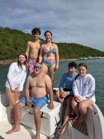 A cheerful family poses together on a boat, enjoying a sunny day on the water — perfect for creating lasting memories during summer adventures.