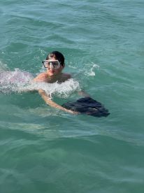 A child enjoys swimming in clear turquoise waters, showcasing a fun snorkeling experience perfect for family adventures.