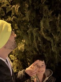 A man and a child are captured in a moment of interaction, surrounded by greenery, but the context and clarity of the image are ambiguous.