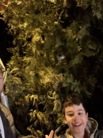 A blurry photo featuring two individuals, one of whom appears to be a child, against a backdrop of foliage. The image lacks clarity and detail.