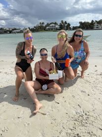 A group of friends celebrates on the beach with champagne and drinks, enjoying a fun day in the sun — perfect for beach parties and gatherings.