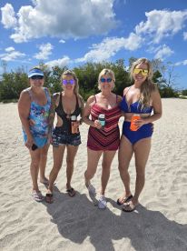 A cheerful group of friends enjoys a sunny day at the beach, celebrating with drinks and smiles — perfect for summer outings and beach parties.