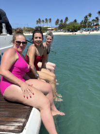 A group of friends enjoys a sunny day by the water, dipping their feet in the turquoise sea — perfect for a fun beach outing.