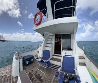 A view of the interior of a boat featuring seating and a helm area, with a crew member visible, showcasing a comfortable space for navigation and relaxation.