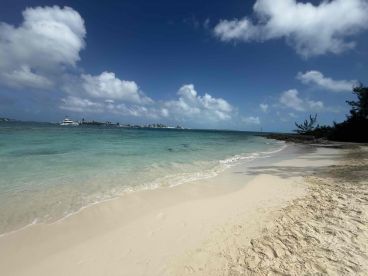 A serene view of a sandy beach with turquoise waters and distant islands, perfect for a relaxing getaway or island hopping adventures.