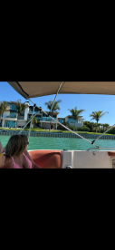A guest enjoys a relaxing moment on a boat, with stunning waterfront properties and palm trees in the background — perfect for scenic boat tours.