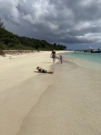 A family enjoys a day at the beach, with children playing in the sand and walking along the shoreline — a perfect setting for memorable summer adventures.