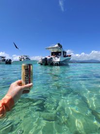 A refreshing moment captured with a drink in hand while enjoying a day on the water, with boats anchored in the background and crystal-clear waters creating the perfect tropical vibe.