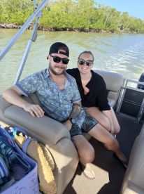 A happy couple enjoys a relaxing moment aboard a boat, surrounded by lush greenery — perfect for a day on the water.