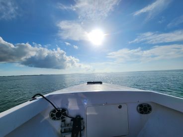 A stunning view from the front of a boat cruising through calm waters under a bright blue sky, perfect for a day of exploration on the water.
