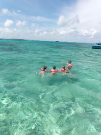 A group enjoys snorkeling in the crystal-clear waters, showcasing a fun day of swimming and exploration in a tropical paradise.