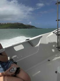 A cozy interior shot of a boat with a guest relaxing and holding a water bottle, showcasing the comfortable seating and helm area.