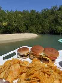 A delicious spread of burgers and chips served on a tray, perfect for enjoying a snack while relaxing by the water in a scenic setting.