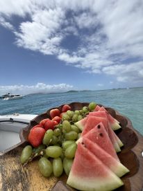 A beautifully arranged platter of fresh fruits including watermelon, grapes, and strawberries, perfect for enjoying on a boat trip in the sun.