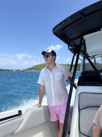 A man enjoys the breeze on a boat, taking in the beautiful scenery — a perfect moment for adventure seekers on the water.