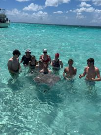 A group of adventurers interacts with a stingray in the clear turquoise waters, showcasing a unique wildlife experience perfect for thrill-seekers.