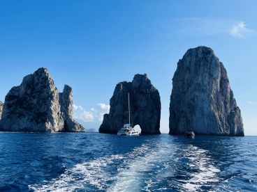 A stunning view of iconic rock formations with boats navigating through the clear blue waters, showcasing the beauty of coastal landmarks.