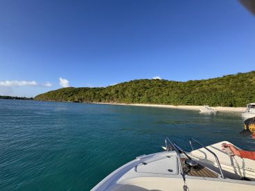 A picturesque view of a serene beach and lush coastline, with a boat anchored nearby, perfect for exploring the tranquil waters.