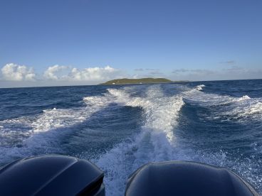 A stunning view of the ocean and a distant island as the boat speeds through the waves, capturing the essence of adventure on the water.