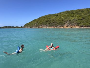 Two individuals enjoy a refreshing swim in the clear turquoise waters, showcasing a perfect day of fun and relaxation in a beautiful natural setting.