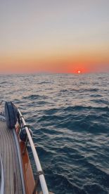 A serene sunset view from the deck of a boat, showcasing the tranquil waters and the horizon — perfect for romantic evening cruises.
