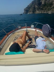 A couple enjoys a relaxing day on a boat, sunbathing and taking in the stunning coastal views — perfect for a romantic getaway on the water.