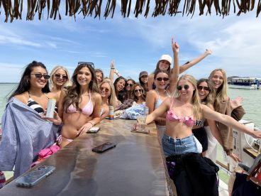 A lively group of friends celebrates together on a boat, enjoying drinks and sunshine — perfect for a fun day on the water.
