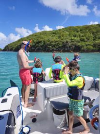A family prepares for a snorkeling adventure on a boat, with kids excitedly getting ready in their life jackets — a perfect day for water activities in a tropical paradise.