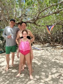 A joyful family poses together on the beach, capturing a memorable moment in a tropical paradise.