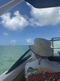 A serene moment on the water as a man enjoys the view from a boat, surrounded by clear skies and gentle waves — perfect for a relaxing day on the ocean.