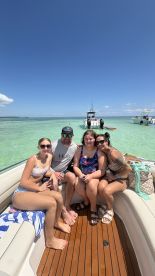 A cheerful group of friends enjoys a sunny day on a boat, capturing the essence of summer fun and camaraderie on the water.
