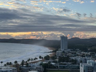 A scenic view of a coastline with clouds and buildings, but the image lacks clarity and focus.