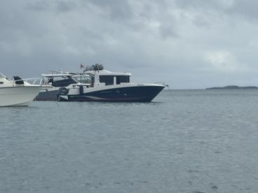 A serene view of a boat docked in calm waters, surrounded by other vessels under a cloudy sky — perfect for showcasing marine adventures.