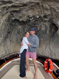 A couple embraces on the deck of a boat inside a stunning cave, capturing a memorable moment during their adventure on the water.
