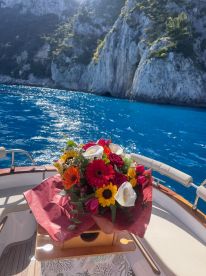 A beautiful bouquet of flowers displayed on a boat, adding a touch of elegance to the maritime experience against a stunning coastal backdrop.