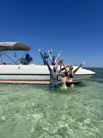 A joyful group of family members celebrates in the clear waters, waving from the boat — a perfect snapshot of fun and togetherness on a sunny day.