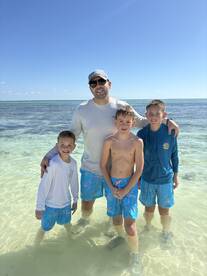 A joyful family poses together in shallow waters, enjoying a fun day at the beach — perfect for creating lasting memories in the sun.