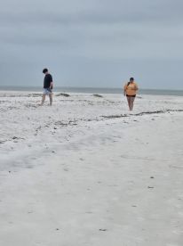 A couple strolls along a serene beach, enjoying the tranquil atmosphere and scenic views of the ocean.
