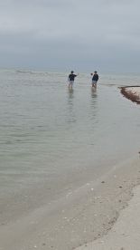 Two individuals enjoy a day at the beach, wading in shallow waters — a perfect setting for relaxation and fun in the sun.