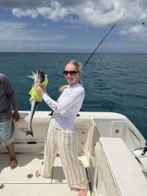 A joyful angler proudly displays her catch aboard a fishing boat, showcasing the thrill of a successful day on the water.
