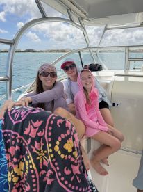 A joyful family poses together on a boat, enjoying their time on the water with smiles and vibrant attire — perfect for memorable family outings.