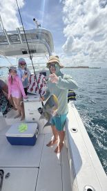 A family enjoys a successful fishing trip on a boat, showcasing a proud catch while soaking up the sun — a perfect day on the water.