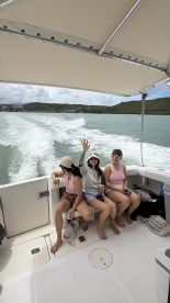 A lively group of friends enjoys their time on a boat, raising drinks and celebrating the moment while cruising through scenic waters.