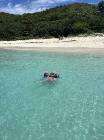 A group of children enjoys a fun day swimming in the crystal-clear waters of a beautiful beach, perfect for snorkeling adventures and family outings.