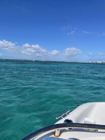 A scenic view from the bow of a boat, showcasing the vibrant turquoise waters and clear blue skies, perfect for a day out on the water.