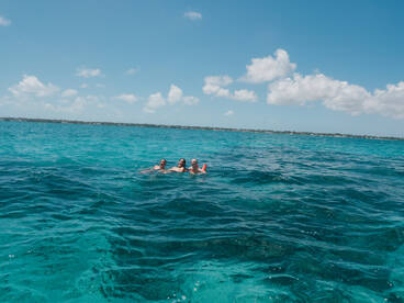 A group of friends enjoys a refreshing swim in the stunning turquoise waters, capturing the essence of a perfect day on the water.