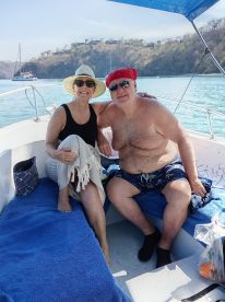 A cheerful couple enjoys a sunny day on a boat, showcasing a perfect getaway experience on the water.