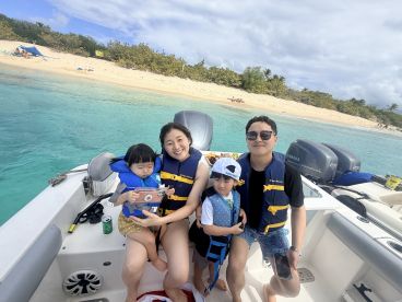 A joyful family enjoys a day on the boat, with kids in life jackets and a beautiful beach in the background — perfect for family outings and beach adventures.